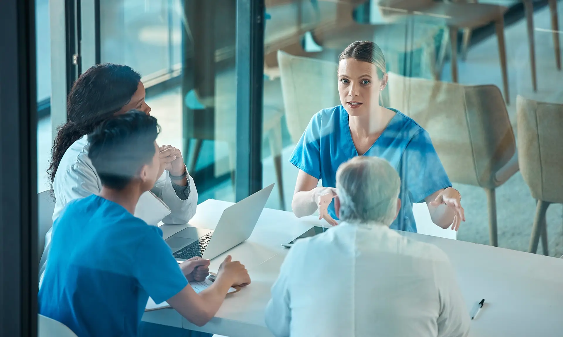 Four healthcare professionals having a discussion at a table in a modern office setting.